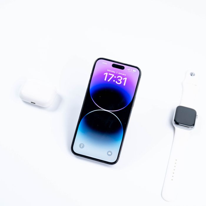 Wireless earbuds next to a smartphone and smartwatch